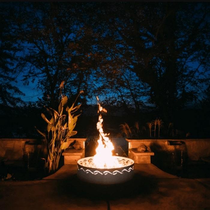 Fire Surfer Stainless Steel Fire Pit by Fire Pit Art with Plants and Tress Background